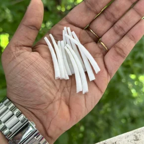 A hand holding white dentalium shells for eco friendly jewelry making